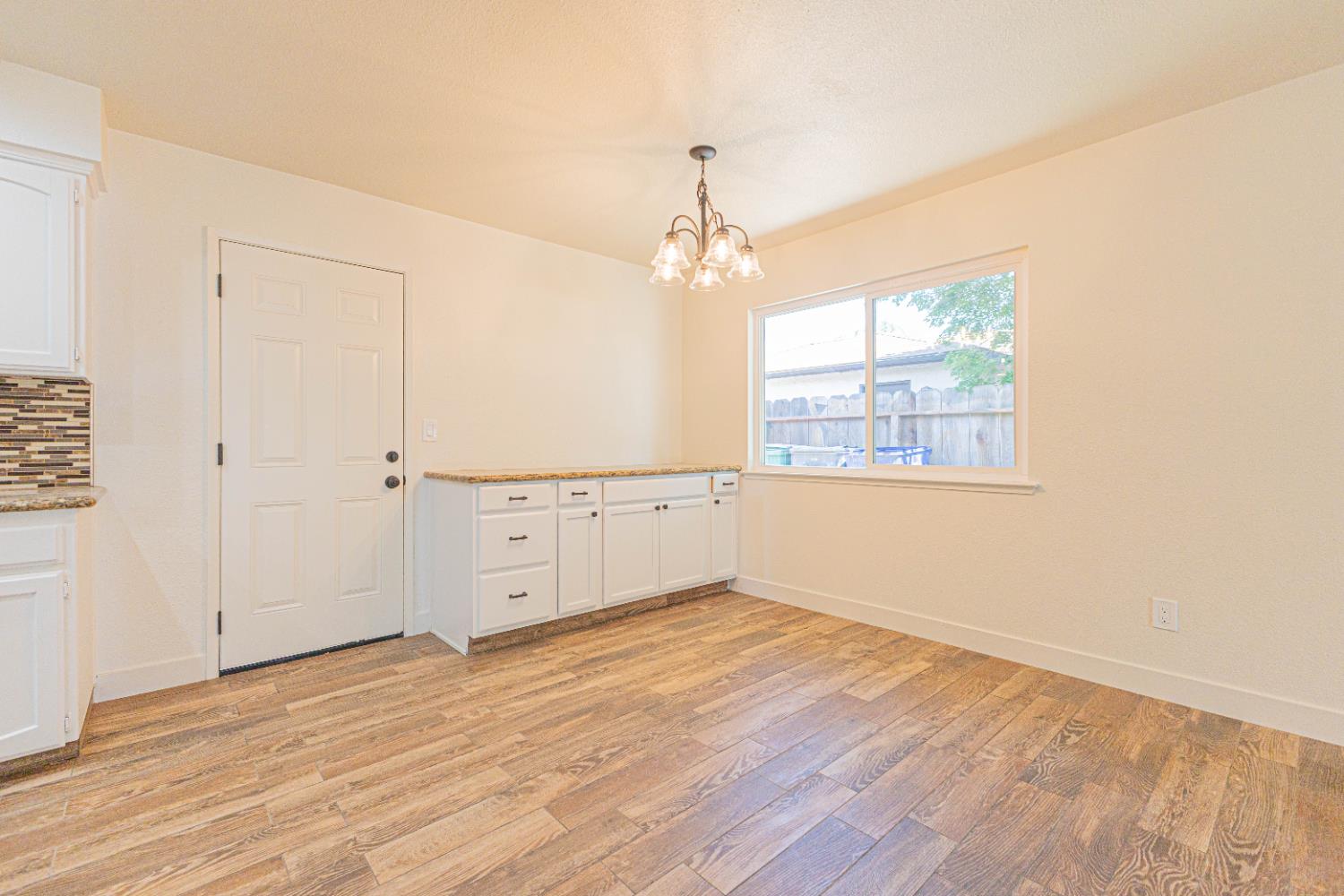 300 Walnut Street Madera, CA 93637 - Photo 4 of 12 an empty room with wooden floor cabinet and windows