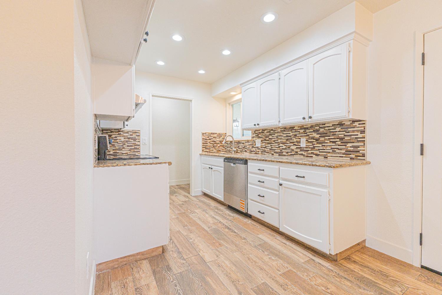 300 Walnut Street Madera, CA 93637 - Photo 5 of 12 a kitchen with stainless steel appliances white cabinets and wooden floor