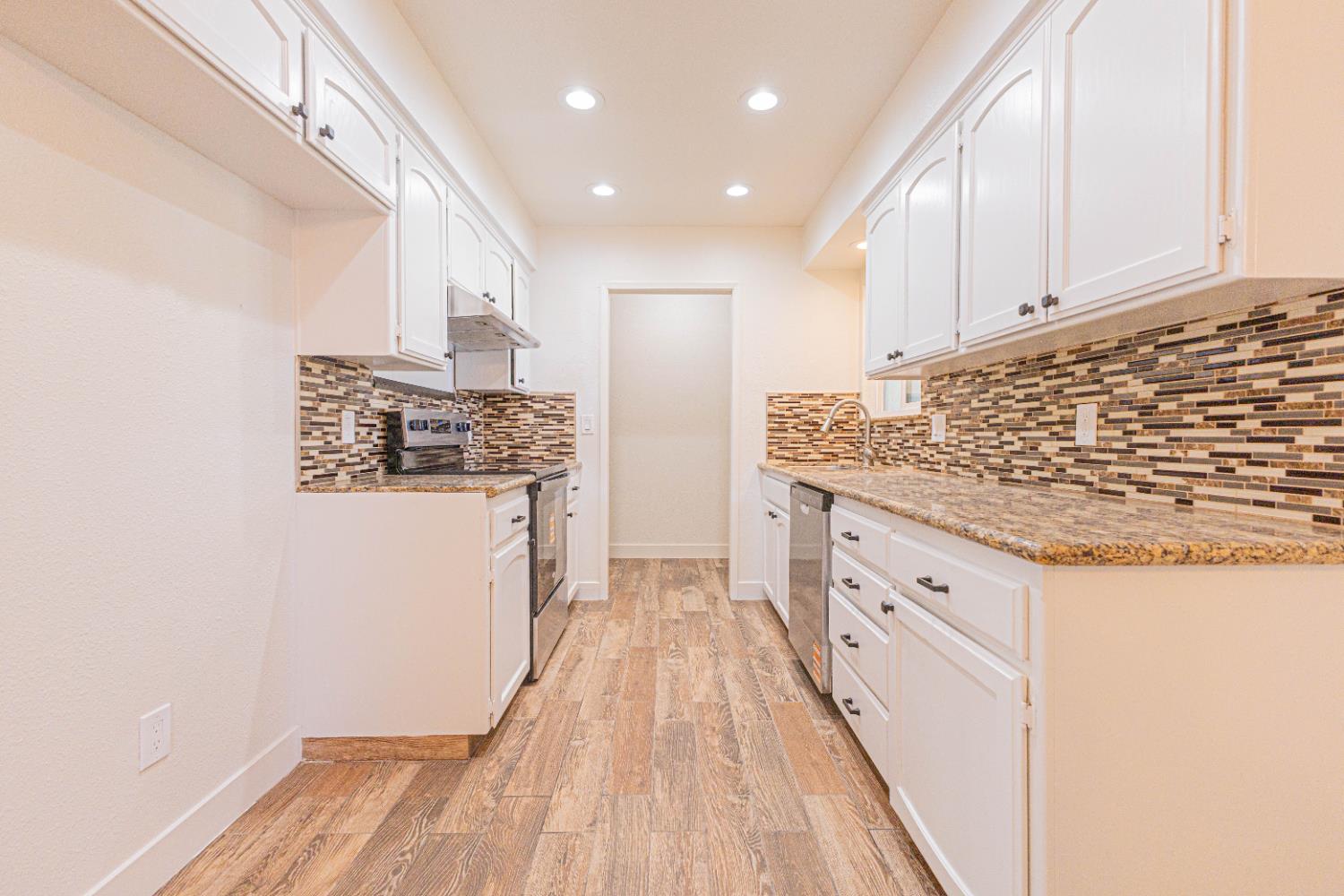 300 Walnut Street Madera, CA 93637 - Photo 6 of 12 a kitchen with granite countertop white cabinets and white appliances