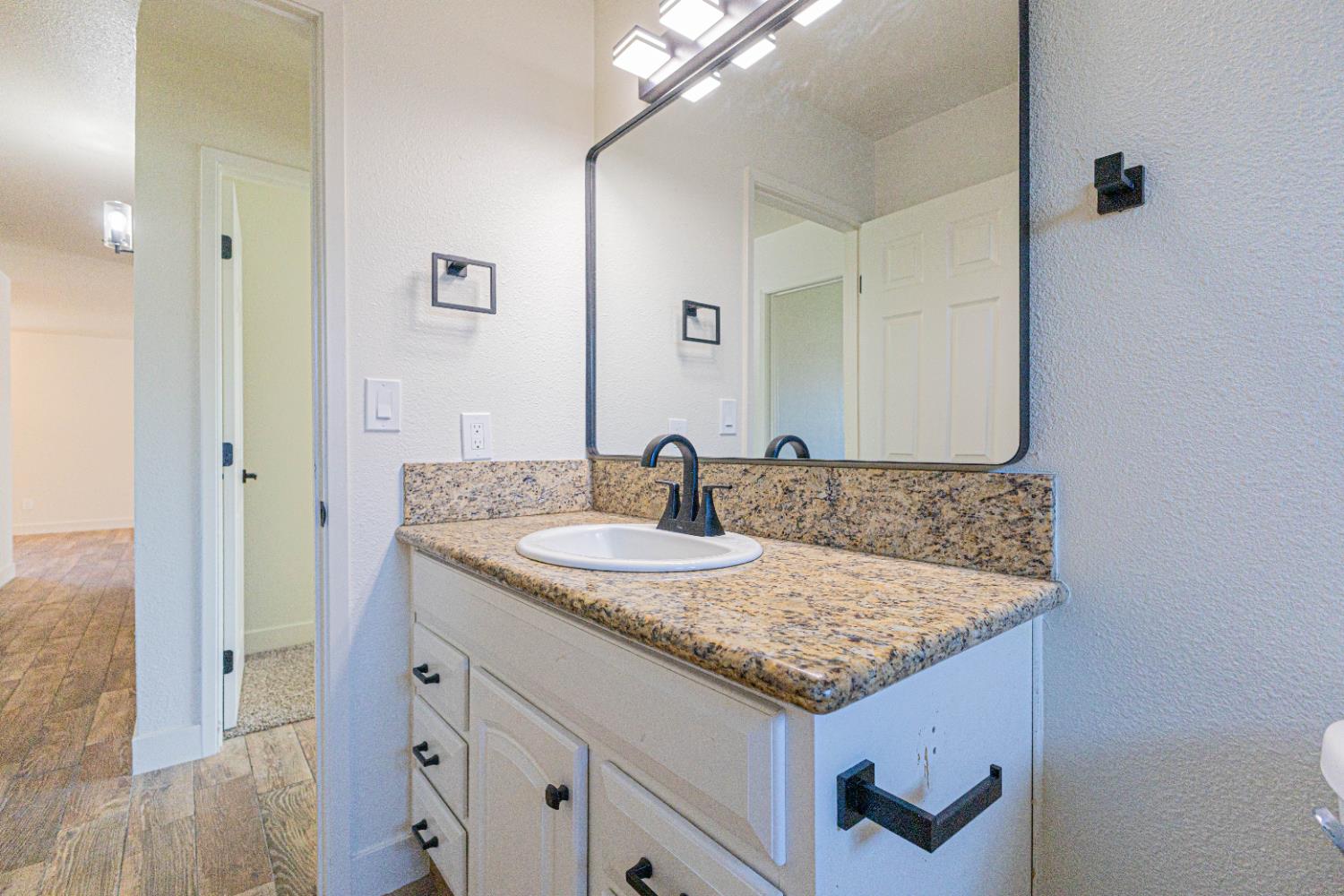 300 Walnut Street Madera, CA 93637 - Photo 10 of 12 a bathroom with a granite countertop sink and a mirror