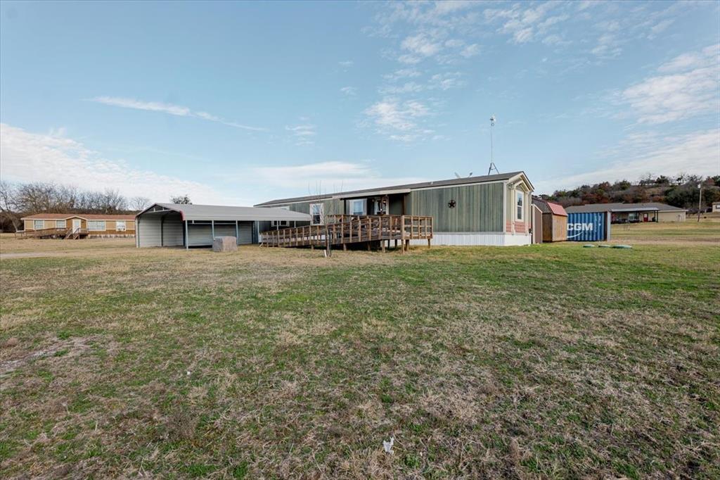 126 Starry Sky Court Springtown, TX 76082 - Photo 28 of 34 Rear view of property featuring a yard, a wooden deck, and a carport