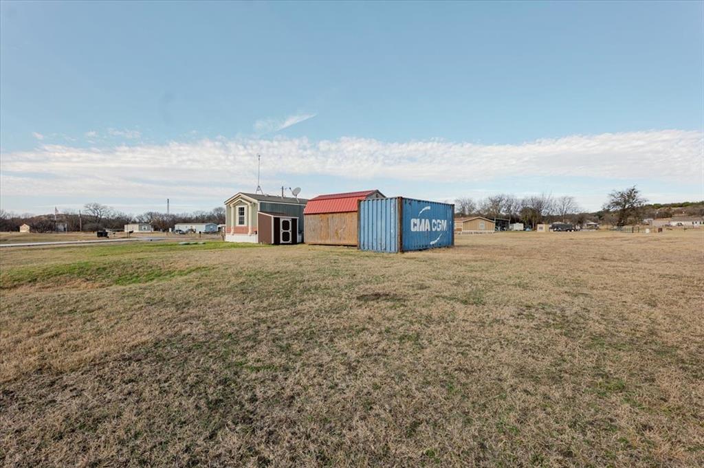 126 Starry Sky Court Springtown, TX 76082 - Photo 30 of 34 View of grassy yard featuring a storage unit and a view of countryside