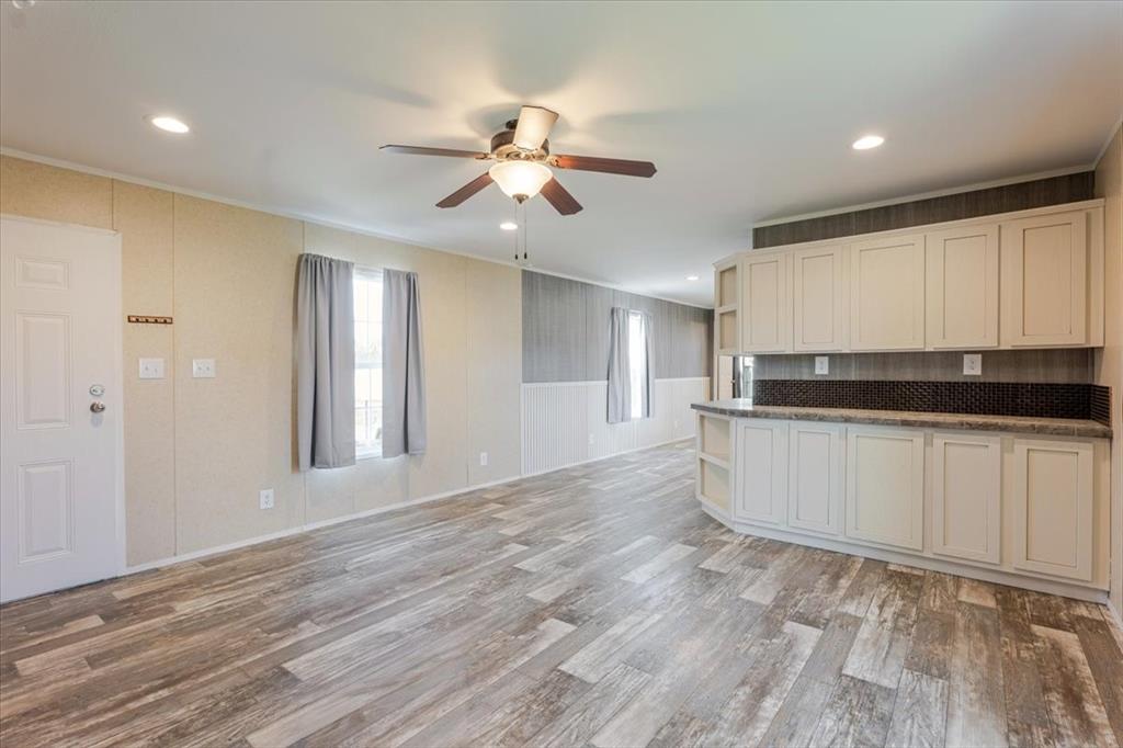 126 Starry Sky Court Springtown, TX 76082 - Photo 5 of 34 Kitchen with dark countertops, light wood-style flooring, a ceiling fan, plenty of natural light.