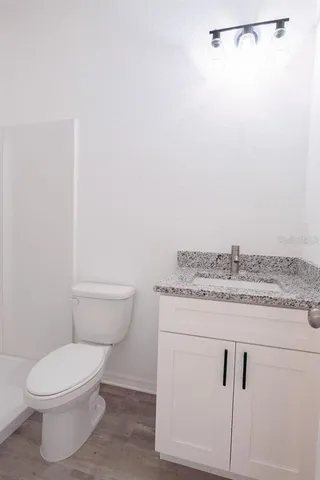 a bathroom with a granite countertop toilet and a sink