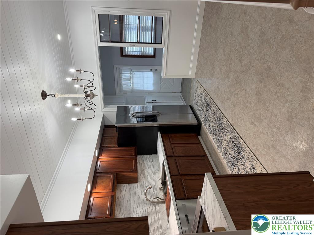 Rich wood cabinetry contrasts beautifully with stone counters and beadboard ceilings in this kitchen.