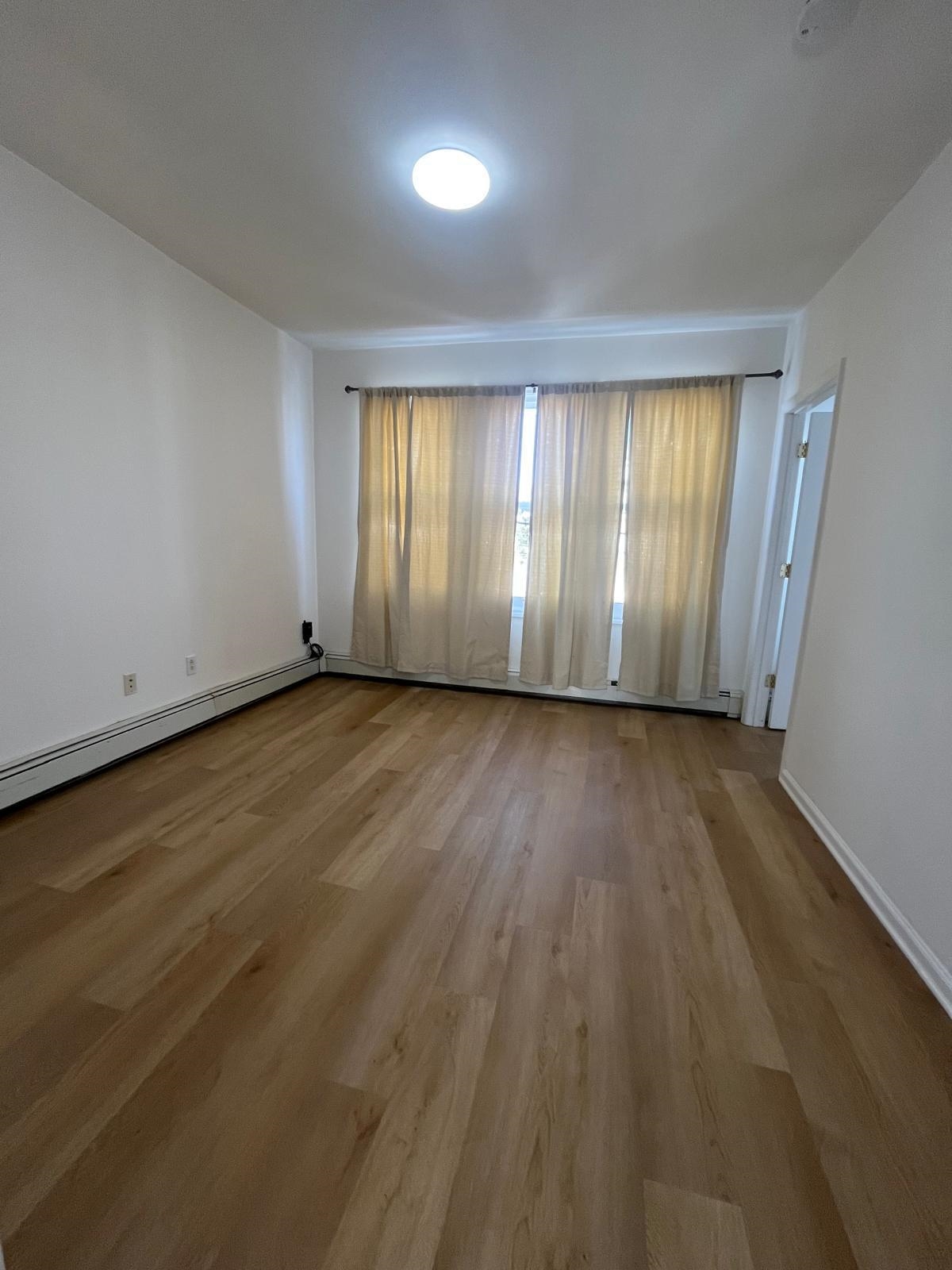 88 Devon Terrace, Unit 2 Kearny, NJ 07032 - Photo 11 of 13 an empty room with wooden floor and windows