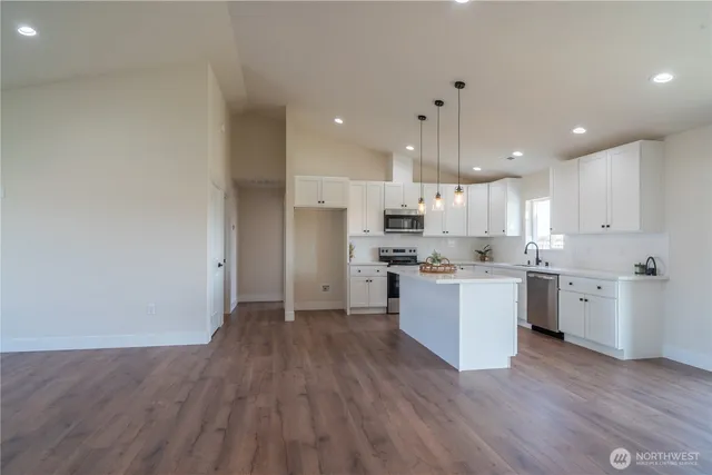 a kitchen with a sink dishwasher and white cabinets with wooden floor