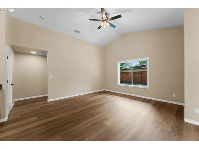 a view of an empty room with a window and wooden floor