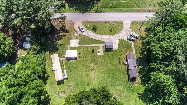 an aerial view of a house with a yard and trees all around