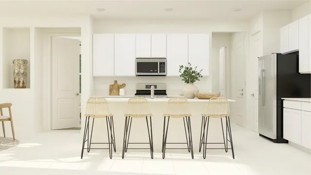 a white kitchen with stainless steel appliances a white table chairs and a refrigerator