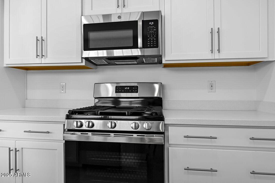 9964 West Piccadilly Road Avondale, AZ 85392 - Photo 17 of 52 a kitchen with stainless steel appliances granite countertop white cabinets and a stove top oven