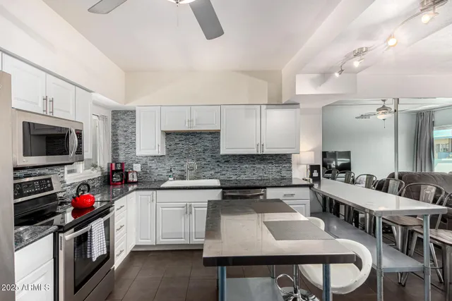 a kitchen with stainless steel appliances granite countertop a stove a sink dishwasher a dining table and chairs with wooden floor