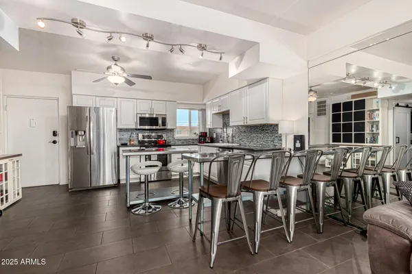 a kitchen with stainless steel appliances kitchen island granite countertop a table chairs sink and cabinets