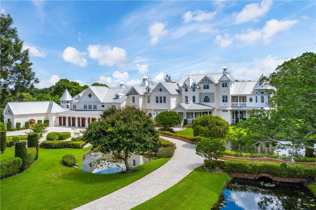 a view of a white house with a big yard and potted plants