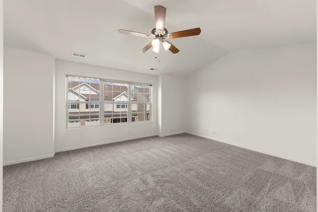 an empty room with fan and windows