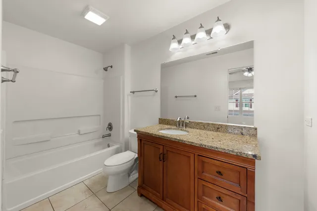 a bathroom with a granite countertop sink a toilet and bathtub