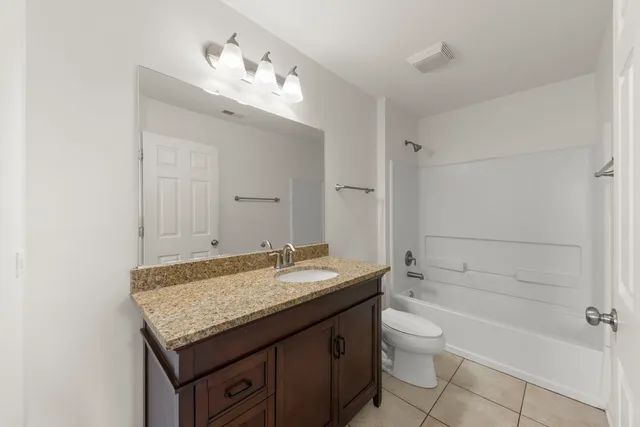 a bathroom with a granite countertop sink a toilet and bathtub