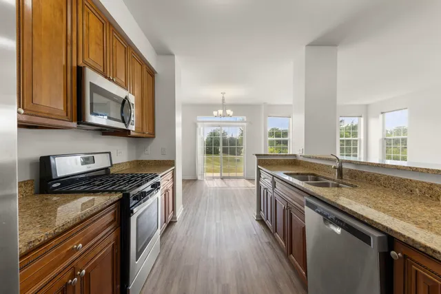a kitchen with stainless steel appliances granite countertop a stove a sink and a microwave