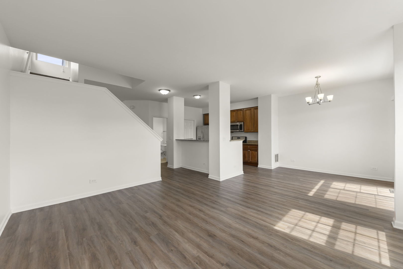 1034 Turin Drive Hampshire, IL 60140 - Photo 9 of 23 a view of an empty room with wooden floor and a kitchen