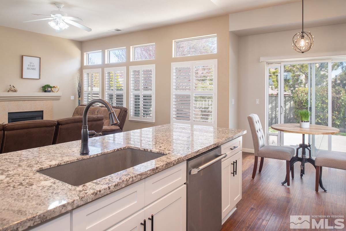 1725 Colavita Way Reno, NV 89521 - Photo 5 of 22 a kitchen with granite countertop a stove a sink a dining table and chairs with wooden floor