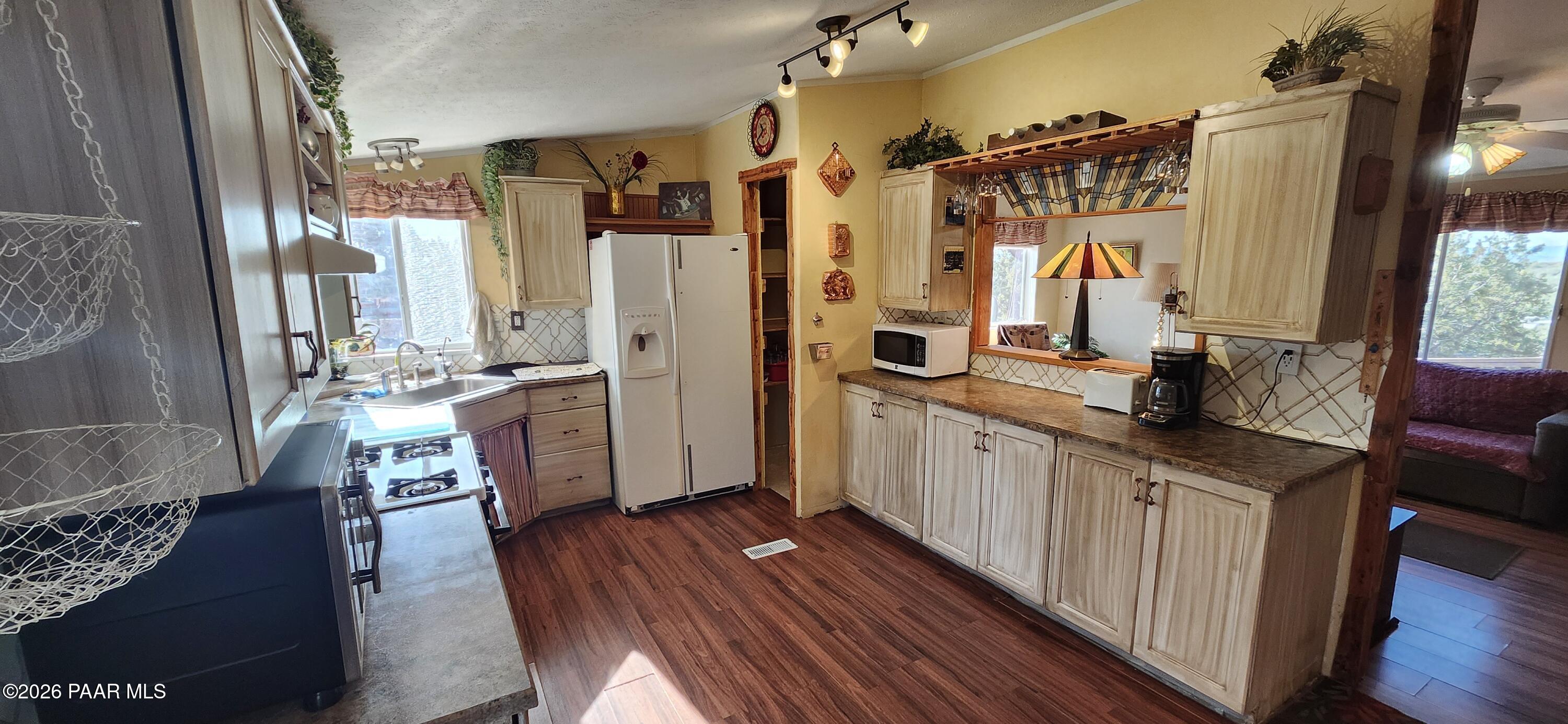 2373 Roberts Road Ash Fork, AZ 86320 - Photo 5 of 41 a kitchen with granite countertop a refrigerator a sink dishwasher a stove and white cabinets with wooden floor