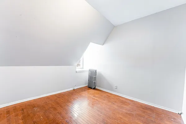an empty room with wooden floor cabinet and windows