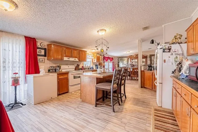 a kitchen with stainless steel appliances kitchen island granite countertop a table chairs and a refrigerator