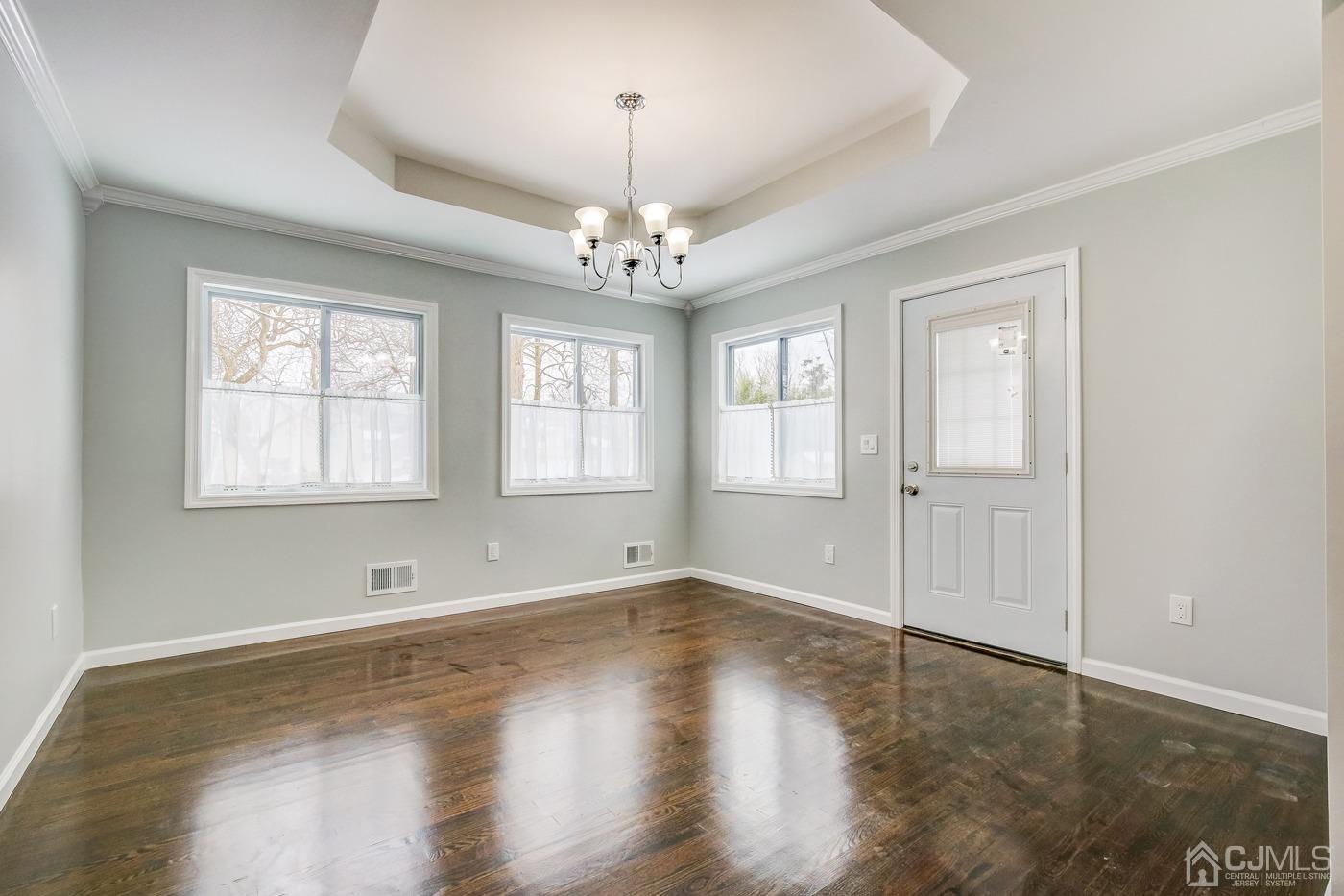 59 Stony Road Edison, NJ 08817 - Photo 14 of 27 an empty room with wooden floor chandelier and windows