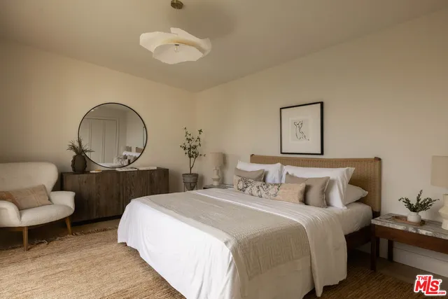 a bedroom with bed a mirror and a potted plant