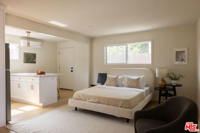 a bedroom with a white bed and dresser with mirror