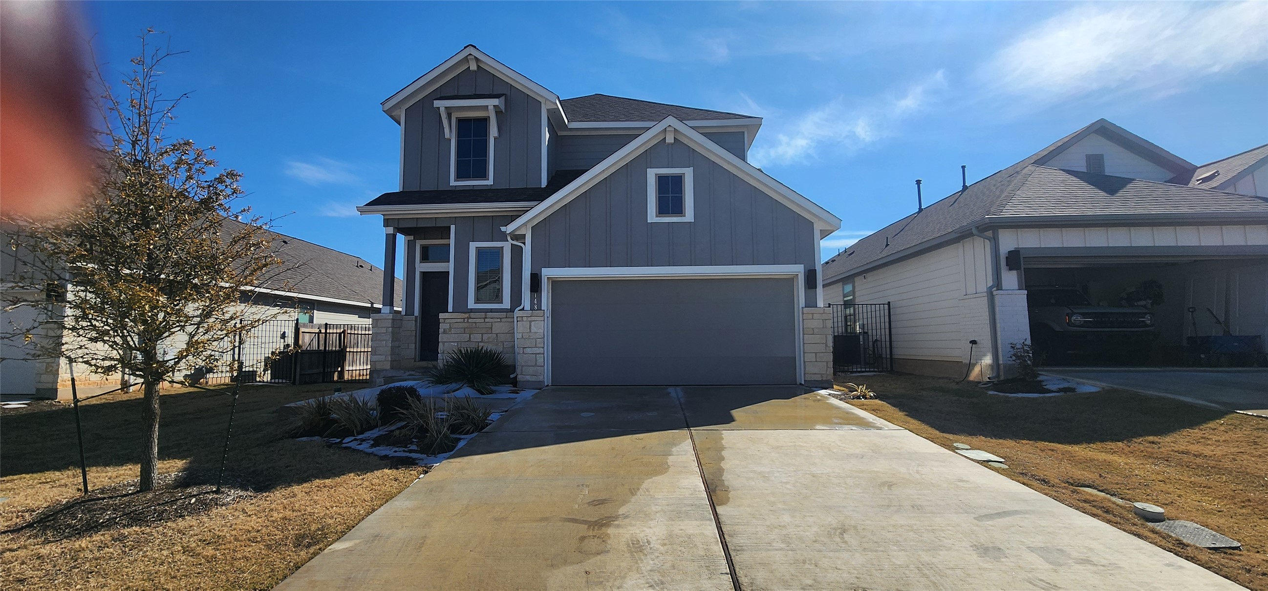 View of front of property with driveway, board and batten siding, and stone siding
