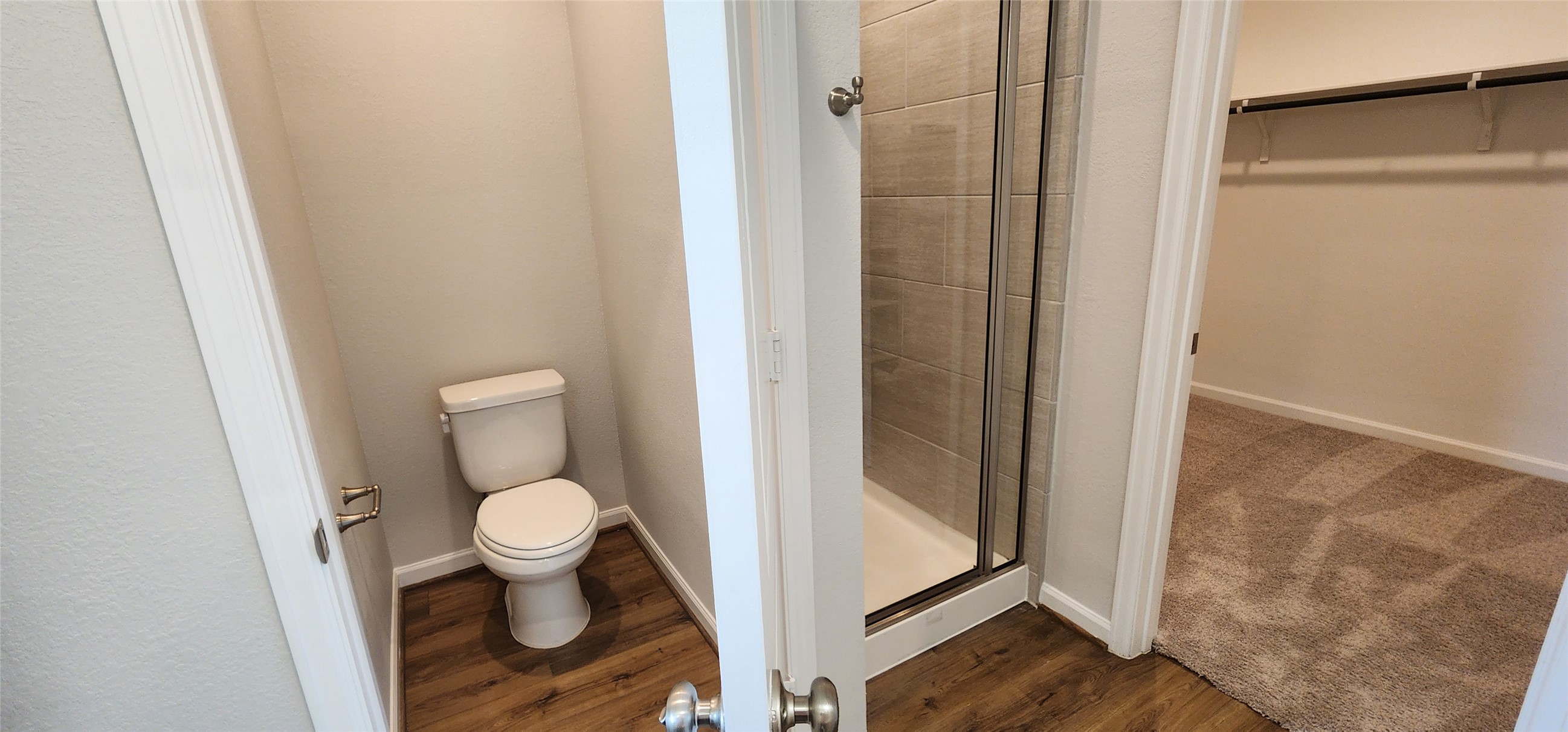 148 Los Olives Lane Georgetown, TX 78628 - Photo 18 of 38 Bathroom with a walk in closet, dark wood-style floors, and a stall shower