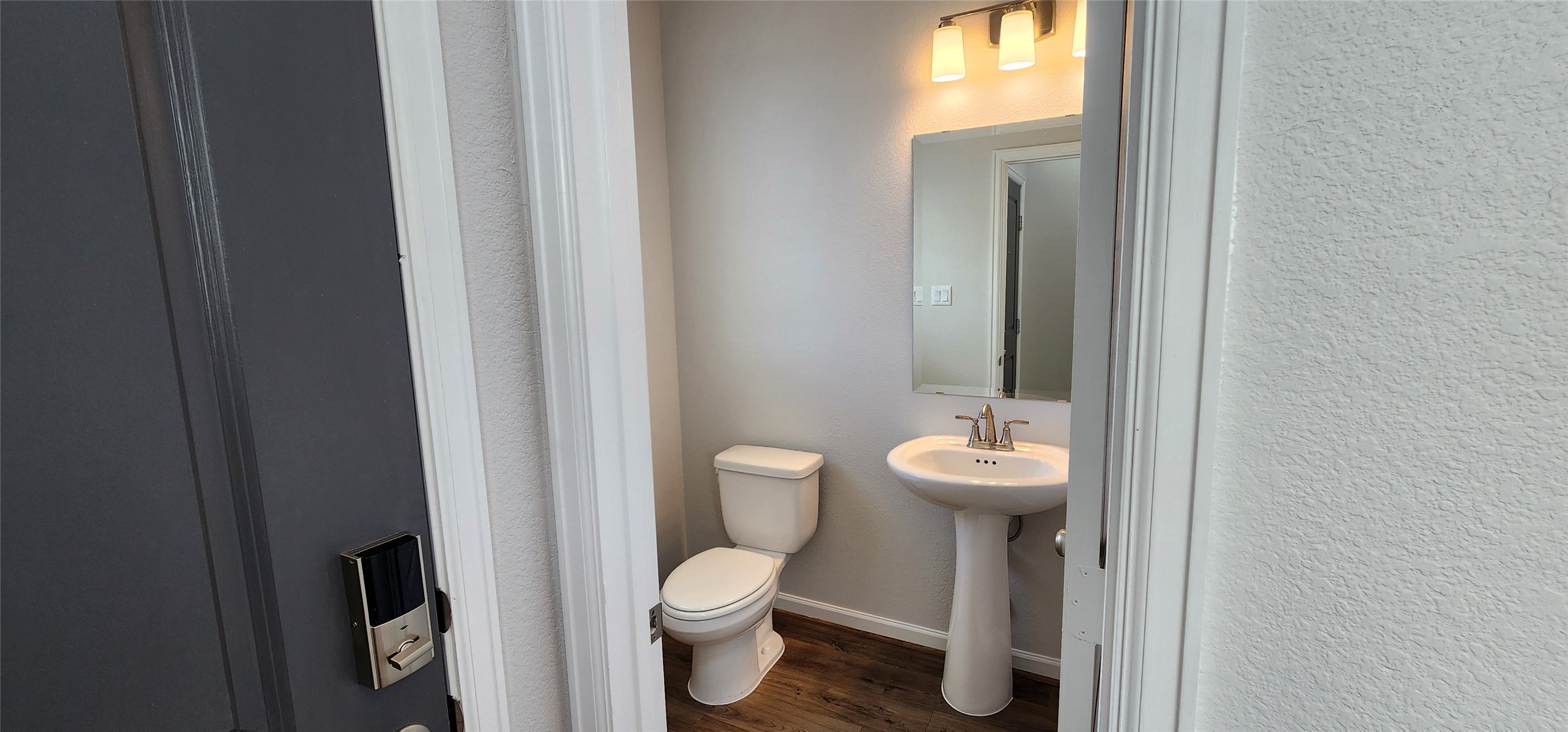 148 Los Olives Lane Georgetown, TX 78628 - Photo 2 of 38 Bathroom with dark wood-style flooring and a textured wall