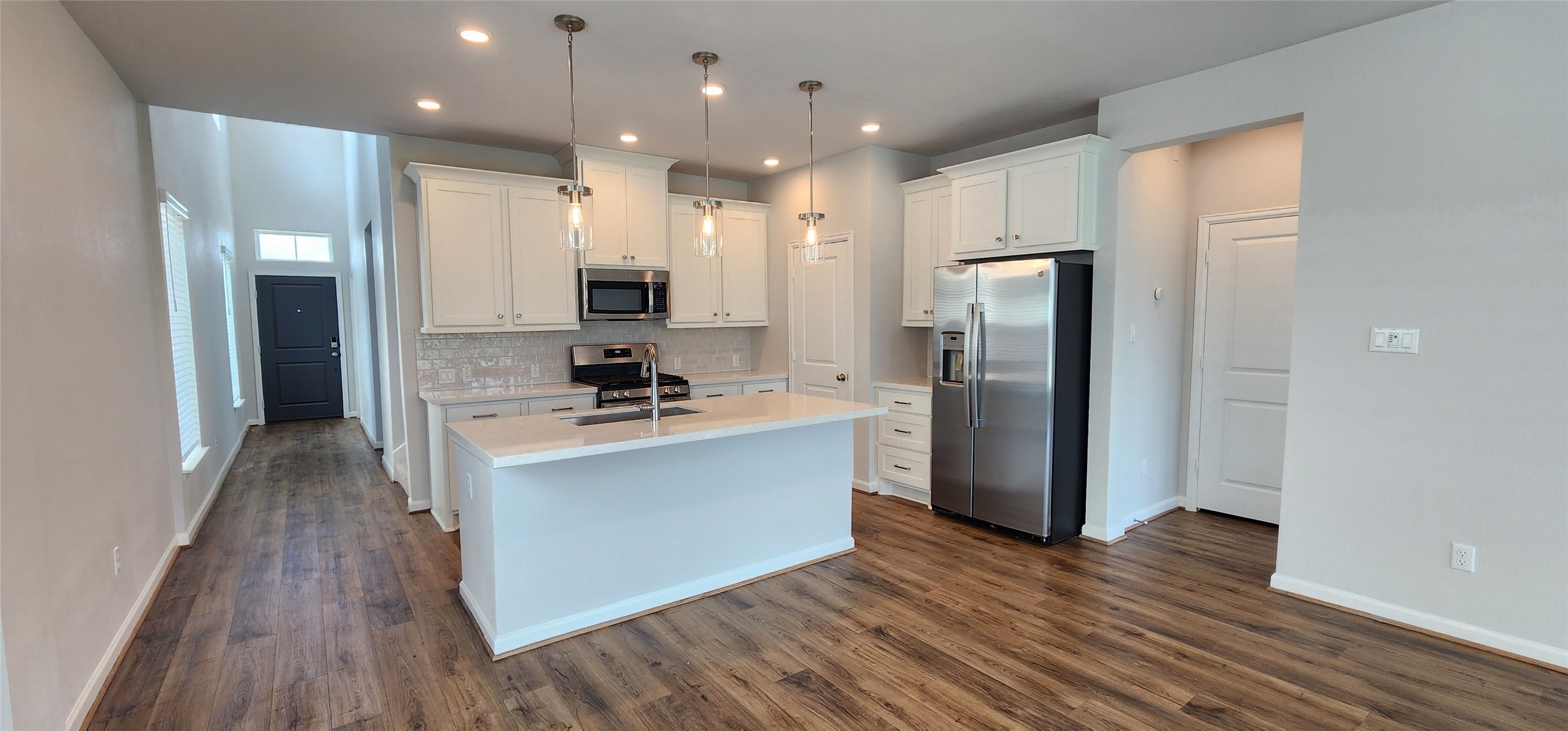148 Los Olives Lane Georgetown, TX 78628 - Photo 9 of 38 Kitchen with stainless steel appliances, white cabinets, a center island with sink, hanging light fixtures, and dark wood-style floors