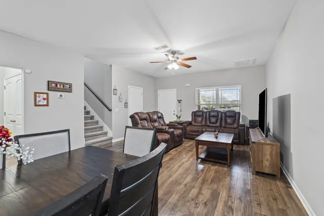 a living room with furniture dining table a lamp and a flat screen tv