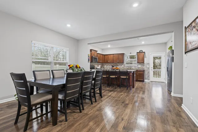 a open dining room with stainless steel appliances kitchen island granite countertop a table chairs and a refrigerator