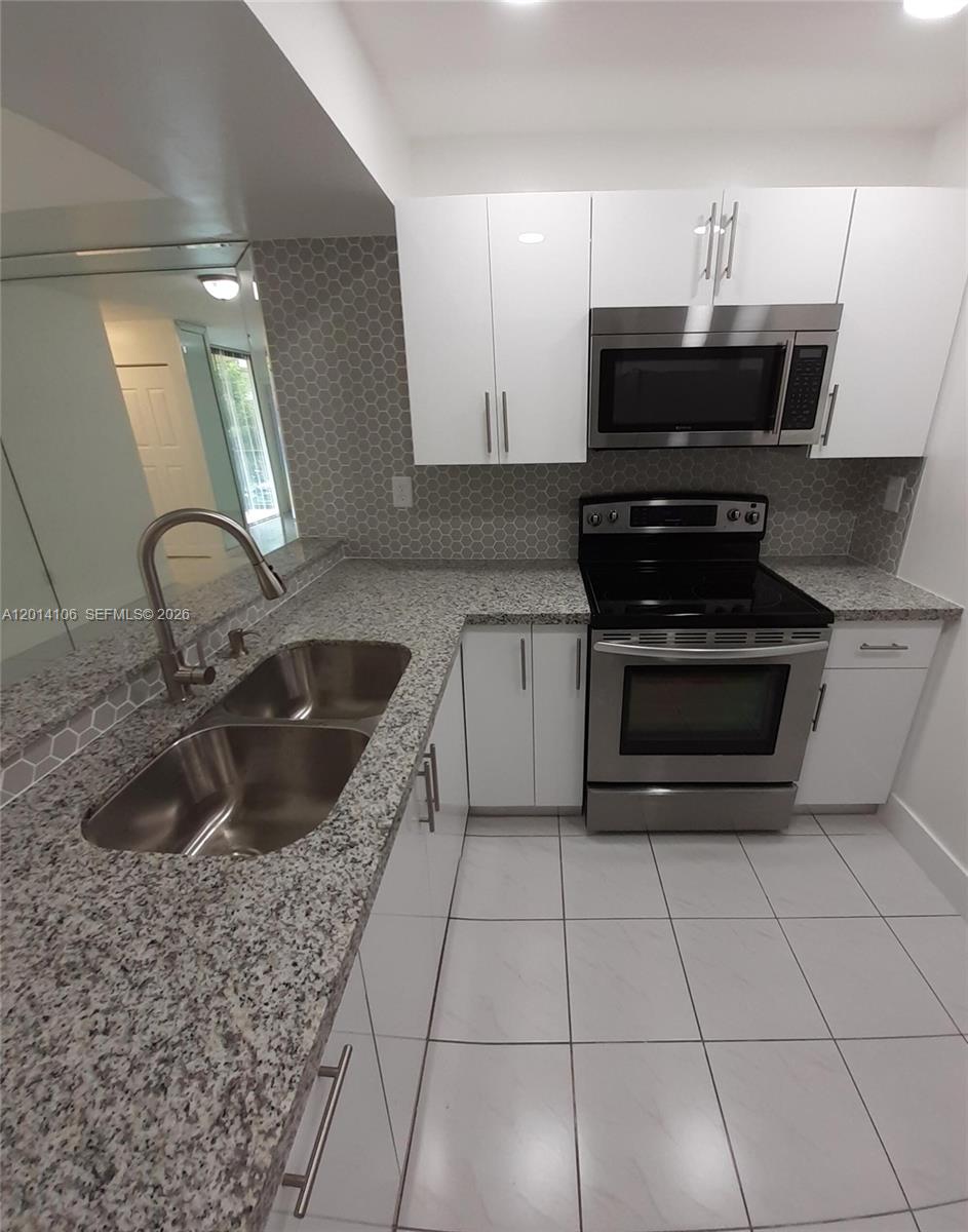 11800 Southwest 18th Street, Unit 3144 Miami, FL 33175 - Photo 2 of 23 a kitchen with a sink a stove and cabinets