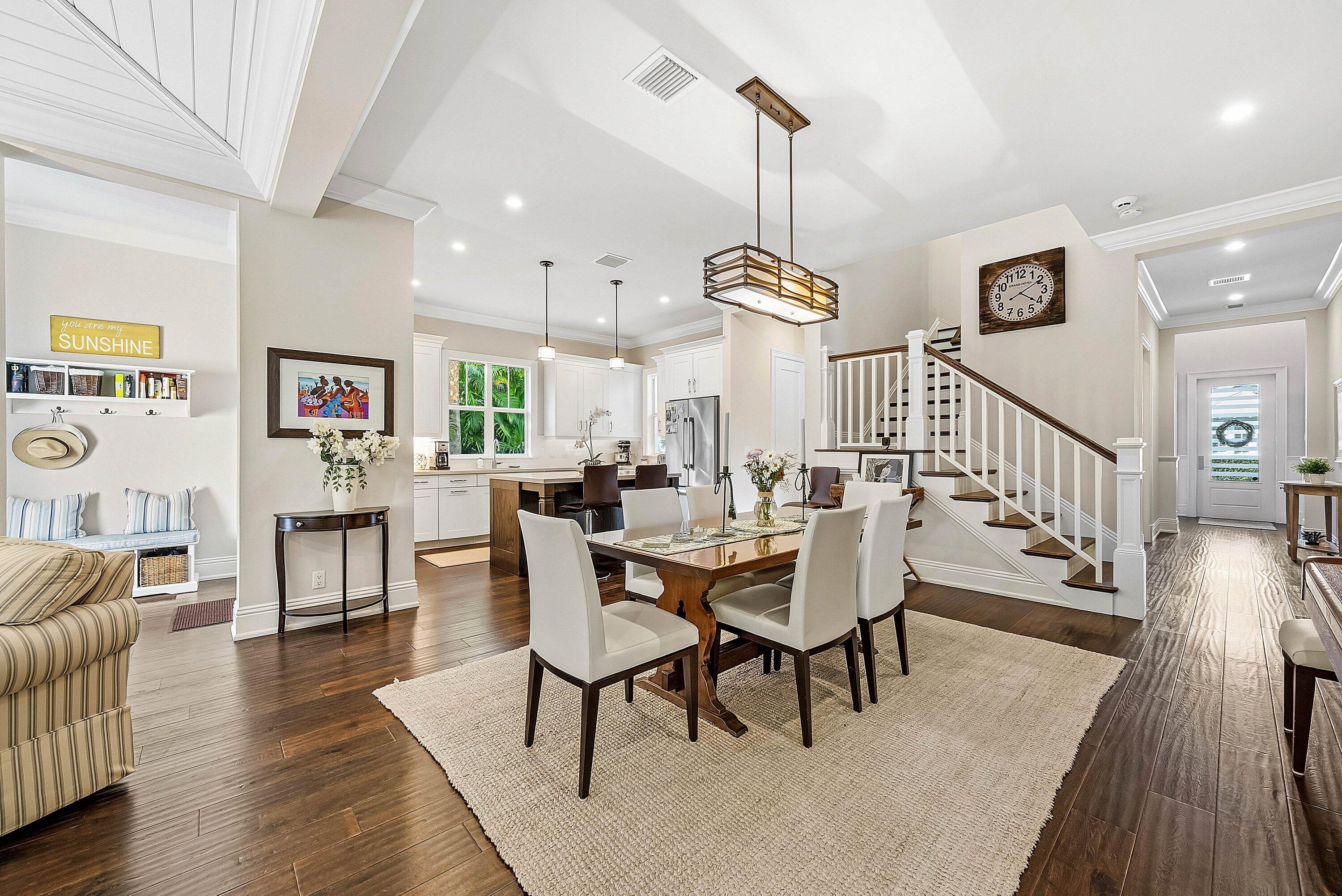 120 Grove Way Delray Beach, FL 33444 - Photo 11 of 43 a view of a dining room and livingroom with furniture wooden floor a rug a flat screen tv a painting and a chandelier