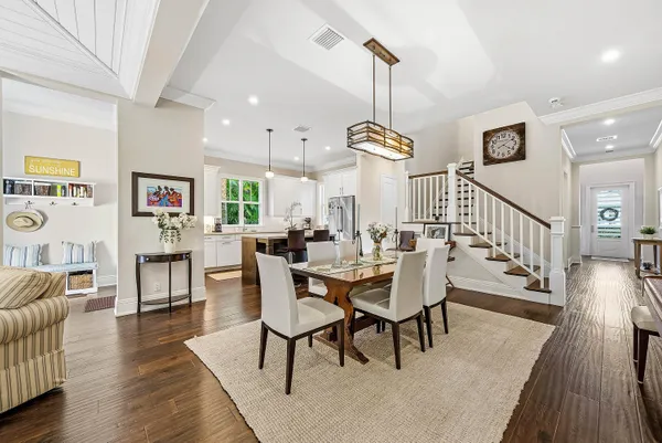 a view of a dining room and livingroom with furniture wooden floor a rug a flat screen tv a painting and a chandelier