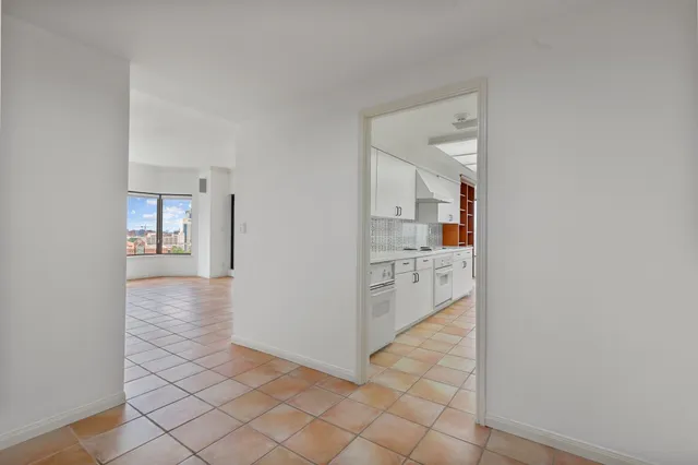 a view of a hallway with white cabinets and wooden floor