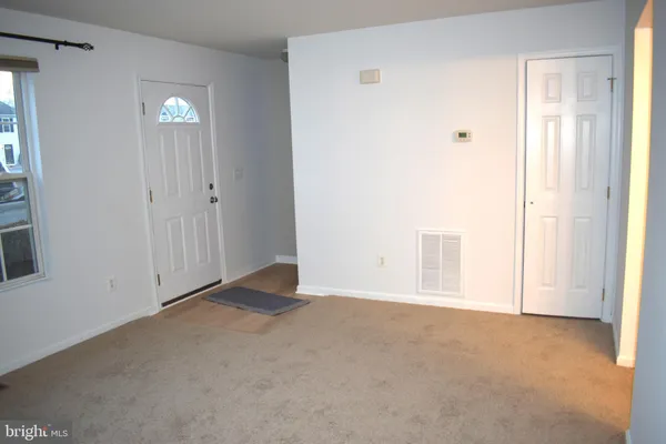 a view of an empty room with closet and a window