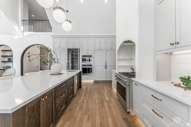 1468 South Red Cliffs Temple Lane St. George, UT 84790 - Photo 18 of 64 Kitchen featuring light stone counters, light wood finished floors, a high ceiling, stainless steel appliances, and two tone cabinets