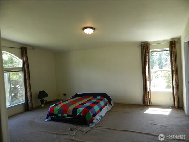 a spacious bedroom with a bed and a flat screen tv
