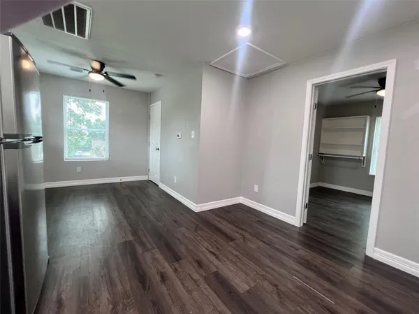 an empty room with wooden floor cabinet and windows