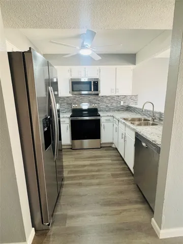 a large kitchen with stainless steel appliances granite countertop a refrigerator a sink a stove top oven a washer dryer and a dining table