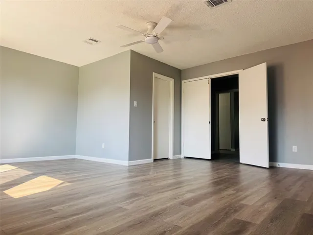 an empty room with wooden floor and a ceiling fan