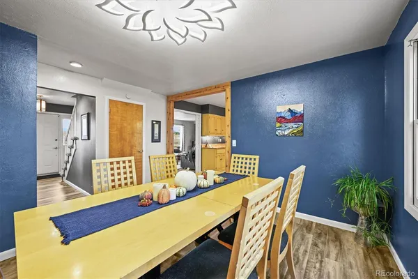 a kitchen with stainless steel appliances granite countertop a refrigerator a sink dishwasher a dining table and chairs with wooden floor