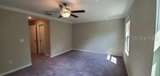an empty room with a ceiling fan and carpet