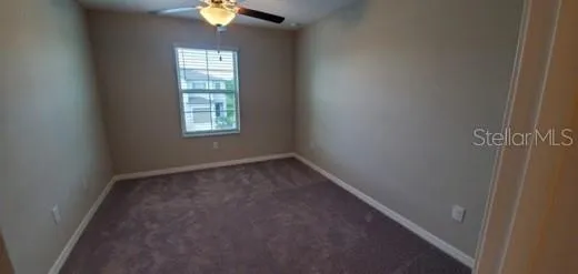 an empty room with windows and chandelier fan