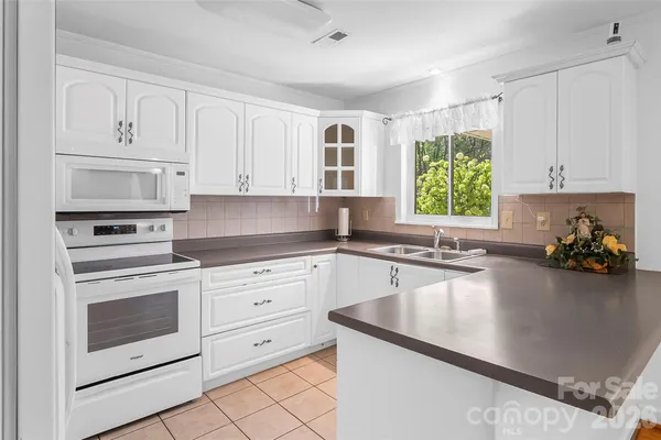a kitchen with granite countertop white cabinets and appliances